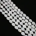 Primer plano macro de cuentas de nácar blanco en forma de hoja con brillo iridiscente - Forma de hoja