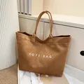 Brown faux suede tote bag with minimalist white TOTE BAG lettering in a room - Brown