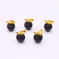 Detail van appelvormige blauwe goudsteen hangers met gouden bladaccenten op wit decor - Blauwe zandsteen