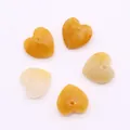 Close-up of five faceted heart-shaped yellow quartz beads for DIY jewelry making - Topaz