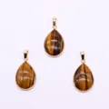 Detailed view of three teardrop-shaped tiger eye stone pendants with golden metal frames - Tiger's Eye