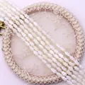 Macro detail of natural spindle-shaped shell beads with pearlescent luster for DIY jewelry - White Shell / White