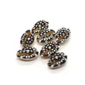 Macro shot of seven black and white cowrie shells with floral patterns for jewelry DIY - Size 6 / 20 Pieces Set