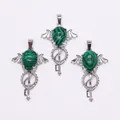 Close-up of angel wing silver key pendants with green malachite stone inlays - Malachite