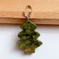 Christmas tree shaped natural green stone pendant with silver clasp on wooden background - Unakite