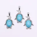 Drie pinguïnhangers met ovale turquoise stenen in zilverkleurige metalen zetting - Blauwe Chalcedoon
