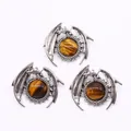 Three dragon-shaped silver metal pendants featuring polished round tiger eye stones - Tiger's Eye