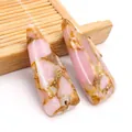 Dettaglio macro di ciondoli a triangolo in pietra rosa e venature dorate per gioielli - Unakite