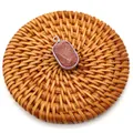 Macro detail of oval goldstone pendant with silver plated edge on woven mat - Gold Sandstone