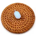 Detail of oval opal glass pendant with silver plated edge on natural rattan mat background - Opal