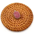 Detail of red agate oval stone pendant with silver-plated rim on a woven mat - Red Wood Grain Stone