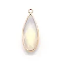 Detailed macro view of a teardrop-shaped white opal stone pendant with gold-plated metal trim - Opal