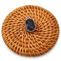 Macro shot of faceted black stone pendant with silver plated bezel on woven rattan mat - Black Agate