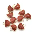 Macro shot of 11 semi-circular red goldstone pendants with polished gold metal framing - Gold Sandstone
