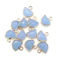 Detailed view of faceted semi-circle opal pendants with golden metal edges and hanging rings - Synthetic Aquamarine