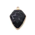Macro shot of shield-shaped black stone pendant with rose gold plating for DIY jewelry - Black Line Howlite