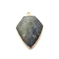 Macro shot of faceted shield-shaped natural stone pendant with electroplated gold edges - Flash Stone (Labradorite)