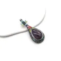 Makro-Detail der lautenförmigen Brosche mit lila Kristall und buntem Emaille-Inlay - Amethyst