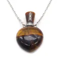 Macro view of heart-shaped tiger eye stone perfume bottle pendant with silver chain - Tiger's Eye