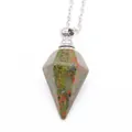 Macro detail of hexagonal Unakite stone pendant on a silver-tone cross chain necklace - Unakite