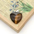 Macro-opname van hartvormige tijgeroog hanger met vintage holle zilveren sluiting - Tijgeroog