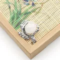 Detail of silver-plated dragon claw pendant holding a white quartz bead with scale texture - White Crystal
