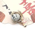 Detailed view of a golden dragon claw pendant holding a spotted natural stone bead - Azurite