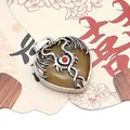 Close-up of a heart-shaped spotted stone pendant with a silver dragon wrap and red gem - Topaz / 32x41mm