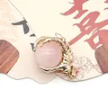 Macro view of gold dragon claw pendant holding a pink quartz stone on display card - Rose Quartz