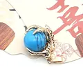 Close-up of golden dragon claw pendant holding a round blue turquoise gemstone - Dark Blue Turquoise