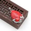 Ciondolo a goccia con pietra rossa e filigrana floreale argento su sfondo in legno retro - Diaspro a Rete Rossa