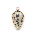 Macro detail of shield-shaped pendant with natural spotted stone and rose gold metal edge - Dalmatian Jasper
