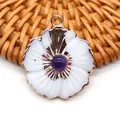 Vue macro d'un pendentif fleur doré avec pétales en coquillage blanc et pierre violette - Améthyste
