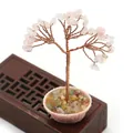 Detalle del árbol de cristal rosa con ramas de cobre y una base decorativa de piedra - Cuarzo rosa