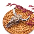Detailed close-up of retro resin bull skull pendant with silver horns on a woven mat - Brown & White Spotted Texture Vintage Style (No. 4)