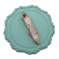 Détail du pendentif quartz rose avec fil doré sur un dessous de verre bleu sarcelle - Quartz rose