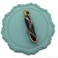 Détail d'un pendentif en onyx noir enveloppé de fil doré fait à la main pour collier - Agate noire