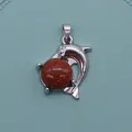 Silver dolphin pendant with round goldstone bead on light blue textured surface - Gold Sandstone