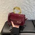 Chic burgundy patent leather shoulder bag with sculptural gold handle and sleek flap closure - Burgundy