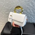 White glossy shoulder bag with a modern gold sculptural handle and slim strap - White