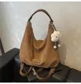 Macro detail of brown suede hobo bag with leather label and soft cloud charm - Brown