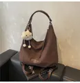 Close-up of dark coffee suede shoulder bag featuring leather logo and cloud charm detail - Brown