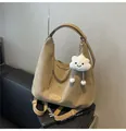 Detail of khaki suede tote bag with plush cloud charm on a black leather sofa - Khaki