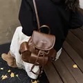 Rückansicht eines dunkelbraunen Lederrucksacks für Damen im Vintage-Stil mit Metallschnallen - Braun