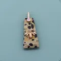 Macro detail of trapezoid natural stone pendant with golden bee and zircon bail - Dalmatian Jasper