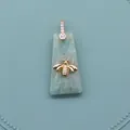 Macro detail of trapezoid natural stone pendant with gold bee motif and zircon clasp - Amazonite