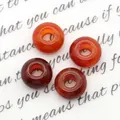 Macro-opname van vier gepolijste rode agaatkralen met groot gat voor DIY-sieraden - Rode agaat