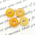 Macro-opname van vier warmgele natuursteen kralen met een centraal gat voor DIY-sieraden - Topaas