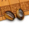 Macro-opname van twee gepolijste ovale tijgeroog cabochons met chatoyancy op bamboe - Tijgeroog