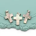 Detailed view of iridescent cross pendants made of natural shell on a green tray - Cross Shape / 14x24mm / Iridescent Black